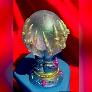 Crystal ball held by green iridescent witchy hands. 4” tall